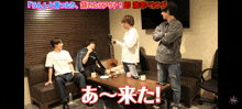 a group of young men are sitting around a table in a room with japanese writing