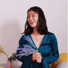 a woman in a blue dress holding purple flowers