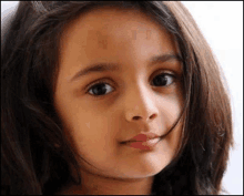 a close up of a little girl 's face with long hair .