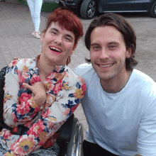 a woman in a wheelchair is laughing next to a man in a white shirt