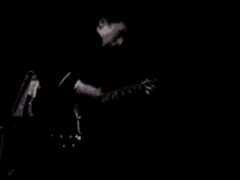 a man is playing a guitar in the dark in a dark room .