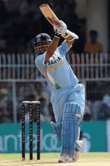 a cricket player is swinging his bat at a ball during a match .