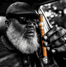 a man with a beard and sunglasses holds a cohiba cigar