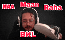 a man wearing headphones holds a shoe in front of the words naa maan raha and bkl