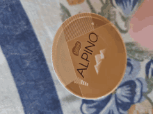 a container of nestle alpino sits on a floral cloth