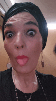 a woman wearing a black turban making a face with her tongue out