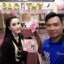 a man and a woman are posing for a picture in a room with balloons and letters that say bac tuy