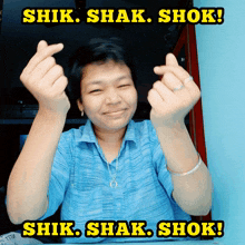 a woman in a blue shirt is making a heart shape with her fingers and the words shik shak shok are above her