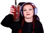 a woman wearing headphones is holding a cup of red liquid with a straw