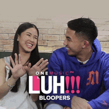 a man and a woman are sitting next to each other in front of a sign that says luh !!! blooopers