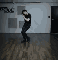 a man in a black shirt is dancing in front of a sign that says brave entertainment