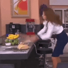 a woman is standing in a kitchen with a popcorn machine and a bowl of bananas on the counter .