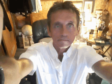 a man in a white shirt is taking a selfie in a room