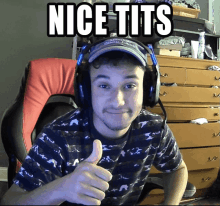 a man wearing headphones and a hat giving a thumbs up with the words nice tits behind him