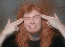 a man with long red hair is making a funny face with his hands to his head