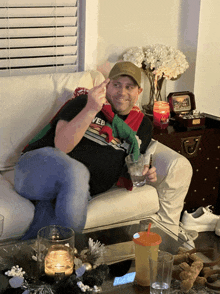 a man sitting on a couch holding a glass and wearing a shirt that says web