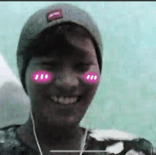 a young man wearing a beanie and headphones is smiling with pink dots on his cheeks .