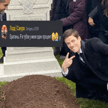 a man in a suit kneeling in front of a grave with a message in a foreign language