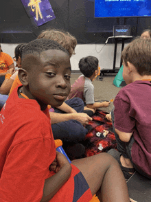 a boy wearing a red shirt that says ' i love you ' on it sits on the floor