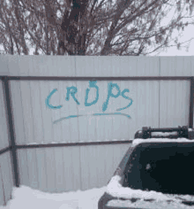 a fence with the word crops spray painted on it in blue .