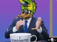 a man in a suit and tie sitting at a table with a cup that says guarantee on it