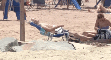 a man laying in a chair on a beach