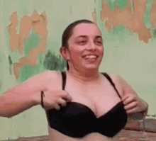 a woman in a bra is taking off her bra and smiling .