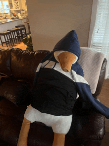 a stuffed duck wearing a hoodie is sitting on a couch next to a home pillow