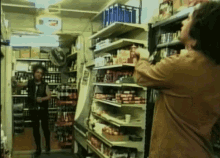 a man in a brown shirt is standing in a store with a coca cola sign on the wall behind him