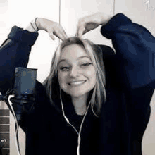 a woman is making a heart with her hands while wearing headphones and a microphone .