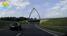 a car is driving down a highway with a bridge in the background and a crying face in the foreground