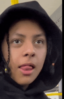 a close up of a person wearing a black hoodie with their tongue sticking out