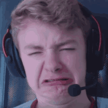 a young man wearing headphones is making a funny face .