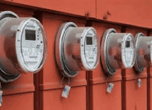 a row of electric meters are sitting on a red wall .