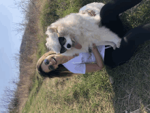 a woman wearing sunglasses is laying in the grass with a dog