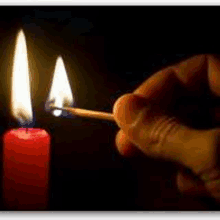 a person lighting a red candle with a match