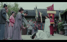 a man kneeling down in front of a group of people with a banner with chinese characters on it