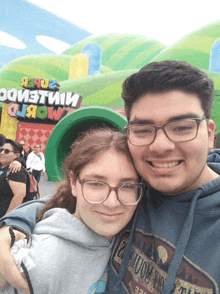 a boy and a girl are posing for a picture in front of a sign that says " mario world "