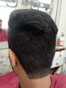 a man getting his hair cut by a barber in front of a mirror