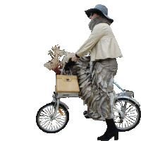 a woman wearing a hat is riding a bicycle with a basket full of flowers