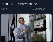 a man in a white coat is pointing at a shelf with music fans when the song comes on written on it