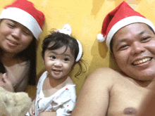 a man and a woman are posing for a picture with a little girl wearing a santa hat