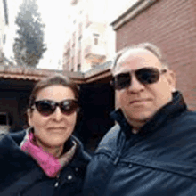 a man and woman wearing sunglasses are posing for a picture .