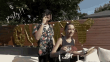 a man and a woman are standing in front of a wooden fence with the words party written on the fence