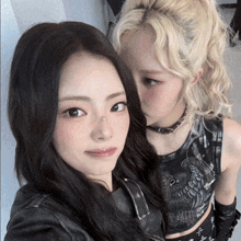 two girls posing for a picture with one wearing a choker and the other wearing a leather jacket