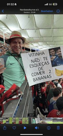 a man holding a sign that says vitinha nao te esquecas de comer 2 bananas