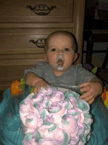 a baby sitting in a walker with a cake in front of him