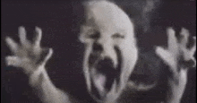 a black and white photo of a baby screaming with its mouth wide open .