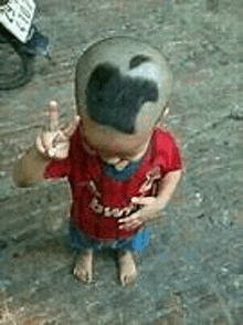 a baby with an apple on his head is standing on the ground .