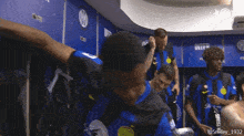 a group of soccer players are standing in a locker room with the number 1932 on the wall behind them